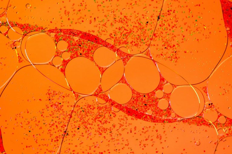 Células en un fondo naranja, con formas ovaladas y burbujas pequeñas.