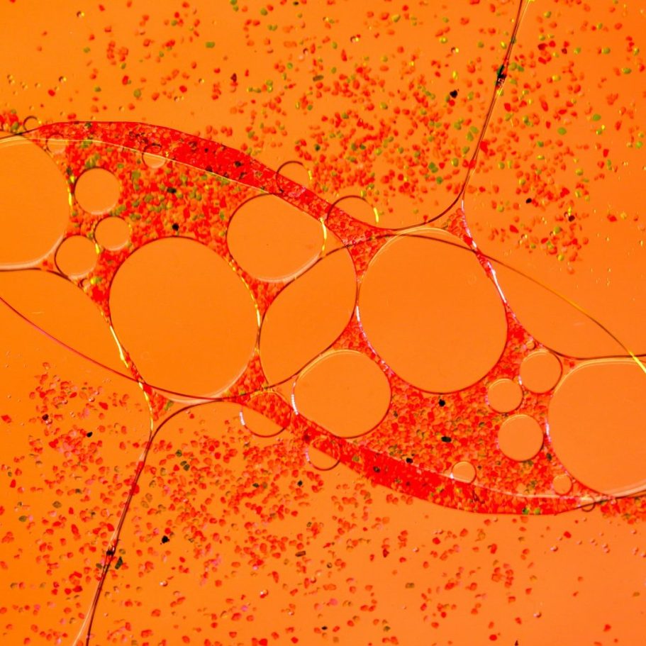 Abstracto en tonos naranjas con burbujas y partículas en un patrón orgánico. Aumento íntimo masculino.