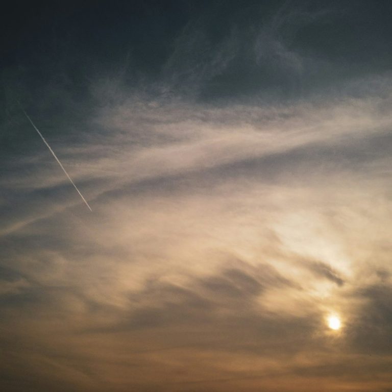 Cielo nublado al atardecer, con tonos anaranjados y una estela de avión. Ozonoterapia